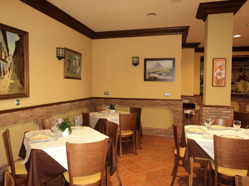 A cozy restaurant interior with warm yellow walls, brick accents, framed artwork, and neatly set tables invites travelers to enjoy a relaxing dining experience.