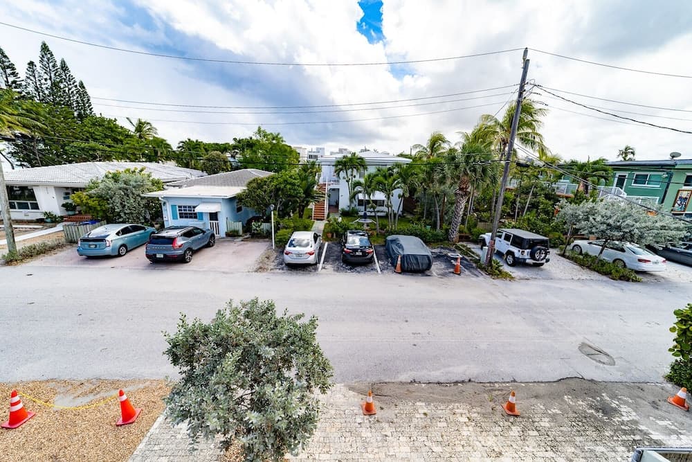 A serene suburban parking area lined with palm trees and colorful cars under a partly cloudy sky, ideal for travelers seeking a tranquil tropical getaway destination.