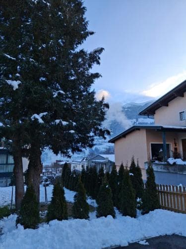 A serene winter scene captures snow-covered evergreens and quaint houses nestled in a mountainous village, ideal for a peaceful ski retreat.