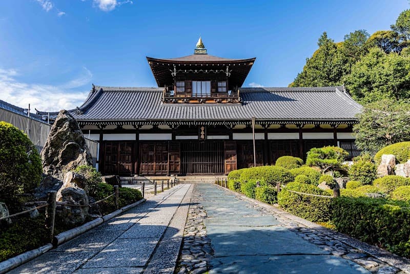 A serene stone pathway leads to the majestic Tōfuku-ji Temple in Kyoto, surrounded by lush greenery and traditional architecture, ideal for cultural exploration and spiritual reflection.