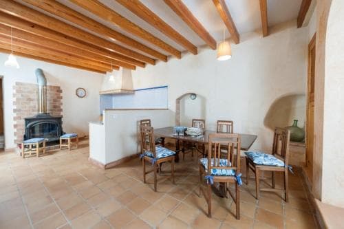 A cozy rustic kitchen with wooden beams, terracotta flooring, and a warm fireplace creates an inviting atmosphere perfect for family gatherings and culinary adventures.