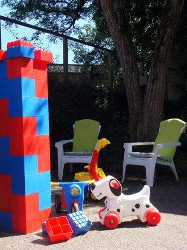 A playful backyard scene features colorful oversized building blocks, whimsical toy chairs, and a charming Dalmatian dog ride-on, perfect for family-friendly outdoor activities and children's play areas.