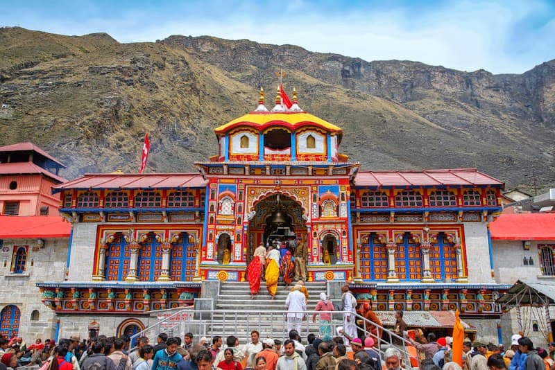 A vibrant crowd gathers at the ornate entrance of Shri Badarinath Dham, set against a majestic mountain backdrop, creating a spiritual and festive atmosphere ideal for cultural and religious tourism in Uttarakhand, India.