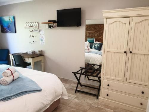 A cozy hotel room features a neatly made bed, a white wardrobe, and a small desk area, creating a welcoming atmosphere ideal for travelers seeking comfort and relaxation.
