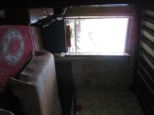 A cozy, rustic room with patterned textiles and a bright window offers a serene retreat, ideal for travelers seeking a quaint and intimate accommodation experience.