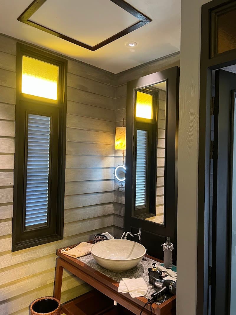 A cozy bathroom at the Anantara Lawana Koh Samui Resort features warm lighting, wooden accents, a stylish bowl sink, and a serene ambiance, perfect for travelers seeking luxury and relaxation in Thailand.