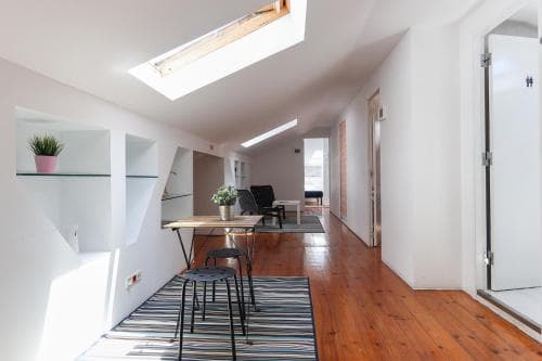 A cozy attic apartment features wooden floors, a skylight, and modern furnishings, creating an inviting atmosphere ideal for a relaxing urban getaway.