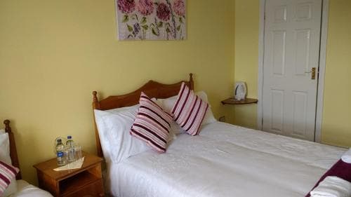 A cozy hotel room with yellow walls, wooden furniture, and floral artwork creates a welcoming atmosphere, ideal for travelers seeking comfort and relaxation.