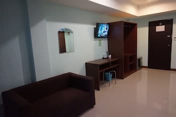 A cozy hotel room features a sleek sofa, a desk with shelving, a mounted TV, and a mirror, creating a serene atmosphere ideal for travelers seeking comfort and functionality.