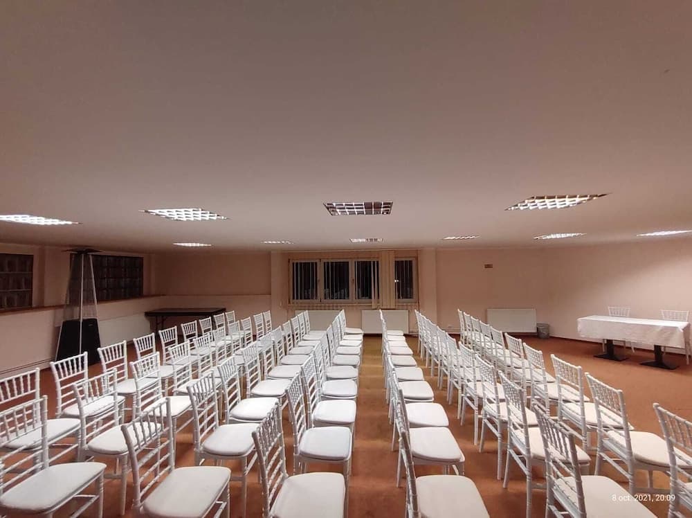 A serene conference room with neatly arranged white chairs under soft lighting, ideal for professional gatherings or educational seminars.