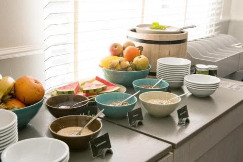 A bright, inviting breakfast buffet setup with fresh fruits, cereals, and neatly stacked bowls on a countertop, perfect for a cozy morning retreat in a vacation rental or hotel.