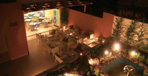 A cozy outdoor patio illuminated by warm lights features comfortable seating around a tranquil poolside area, ideal for evening relaxation at a boutique hotel.