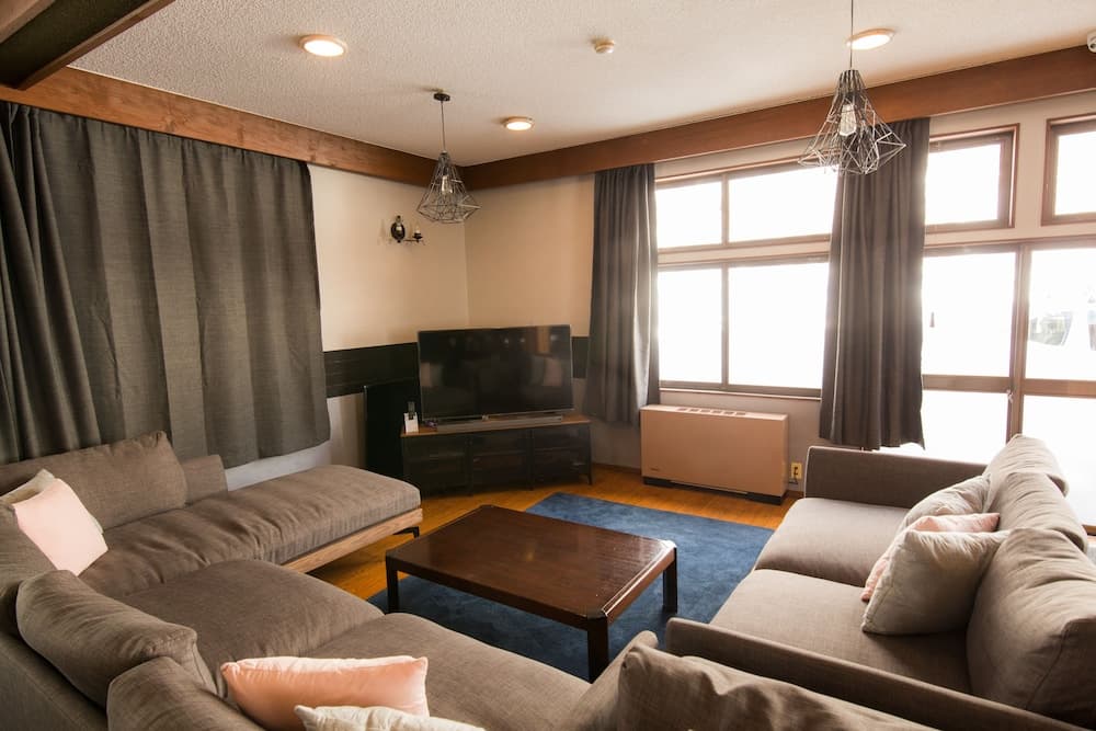 A cozy living room with plush sofas, a wooden coffee table, and large windows inviting natural light, ideal for travelers seeking a comfortable and relaxing accommodation space.