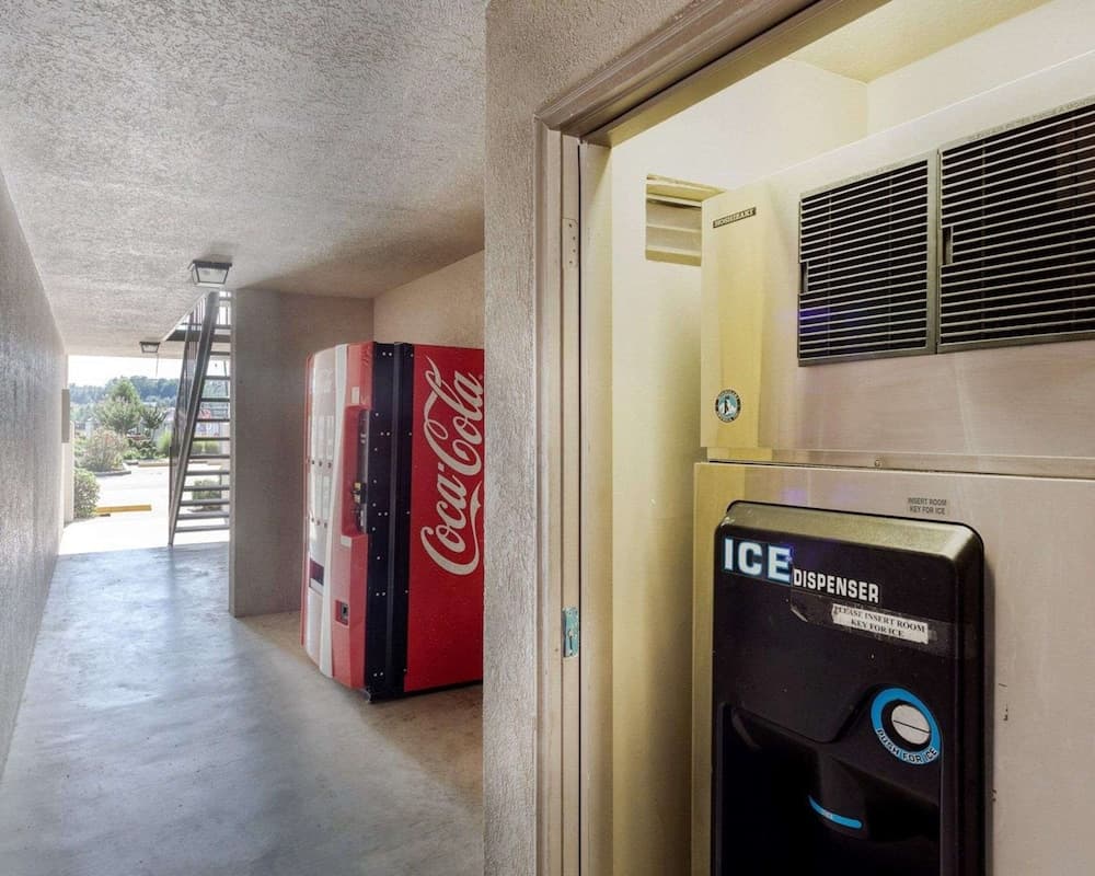 A cozy motel corridor features a vibrant Coca-Cola vending machine and an ice dispenser, creating a convenient and inviting atmosphere for travelers seeking refreshments.