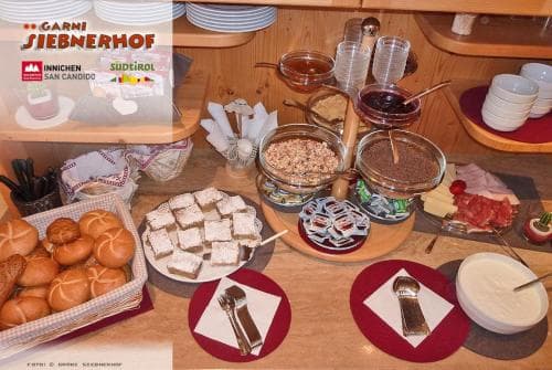 A cozy breakfast buffet scene at a rustic inn features an array of pastries, cheeses, spreads, and condiments on wooden tables, inviting travelers to indulge in a hearty morning meal.