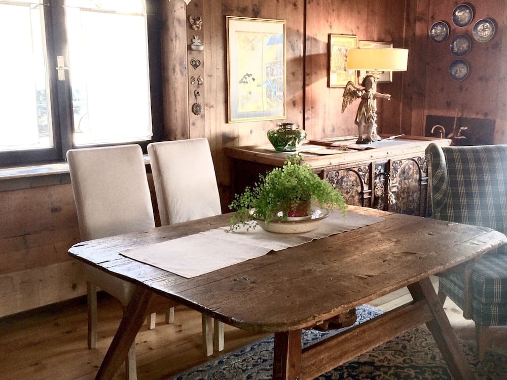 A cozy rustic dining room with wooden walls, a vintage table adorned with greenery, and eclectic decor creates a warm, inviting atmosphere perfect for travelers seeking a charming countryside retreat.