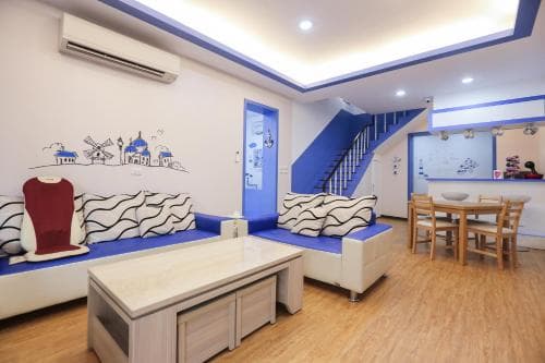 A cozy, modern living space with blue accents, a staircase leading to an upper level, and Mediterranean-themed wall art creates a welcoming atmosphere ideal for travelers seeking a comfortable and stylish accommodation.