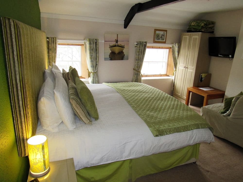 A cozy bedroom with green accents, soft lighting, and nautical artwork creates a serene retreat ideal for travelers seeking relaxation in a charming lodge setting.