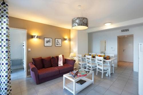 A cozy apartment living space features warm lighting, a plush sofa, dining area, and modern decor, ideal for travelers seeking comfort and style in their accommodations.