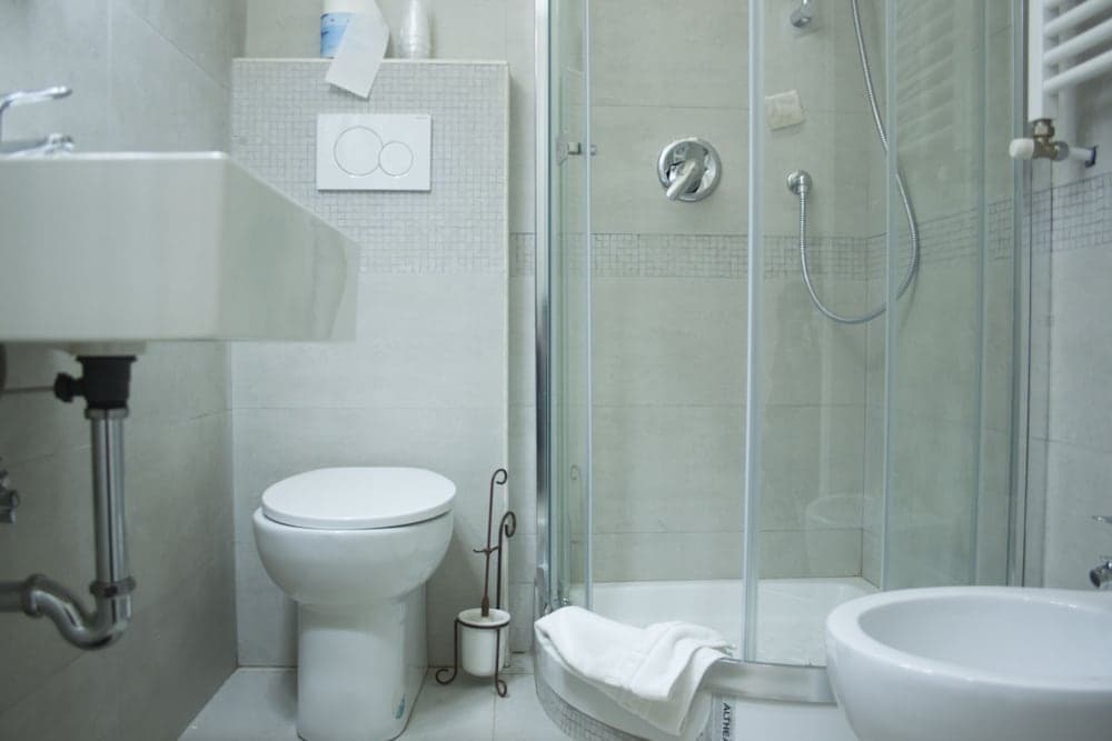 A clean, modern bathroom with a glass-enclosed shower, white fixtures, and tiled walls offers a serene and functional space ideal for travelers seeking comfort and hygiene.