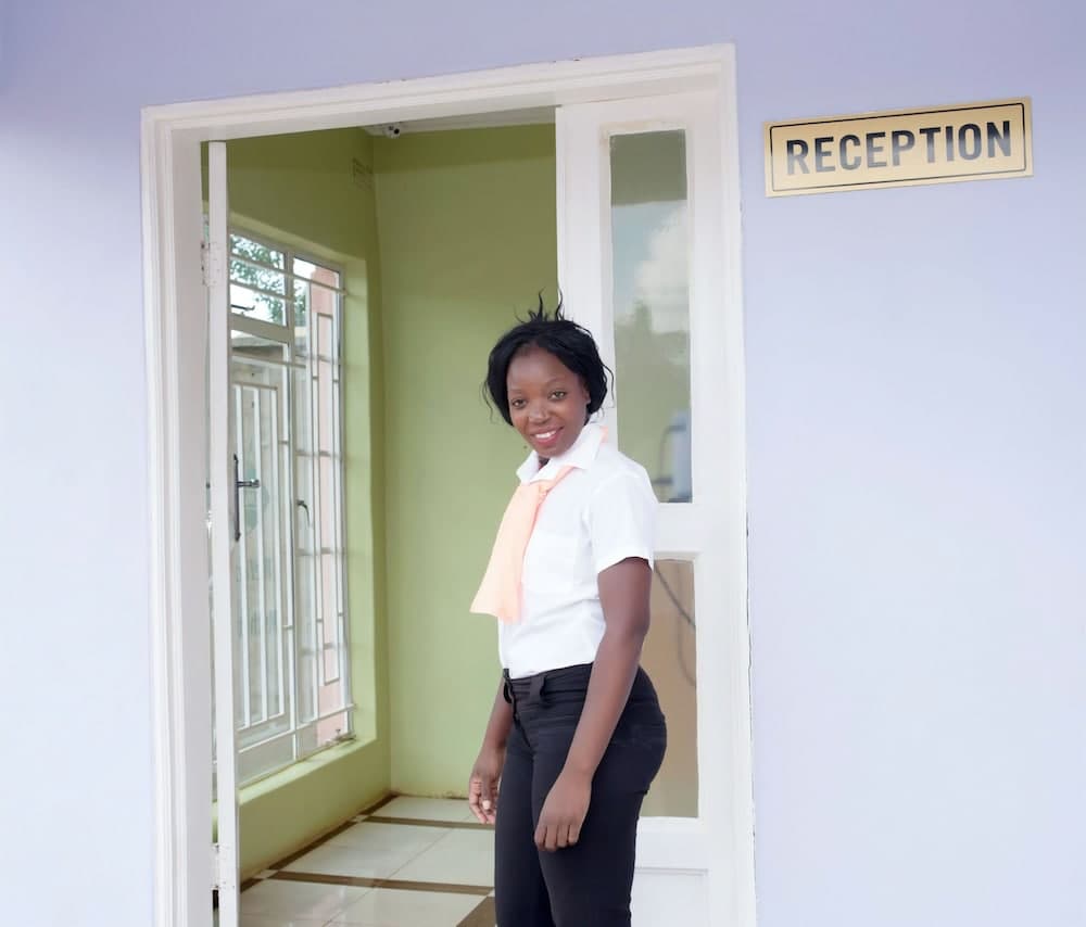 A welcoming reception area features a smiling individual in professional attire standing by an open door, ideal for travelers seeking assistance or information at a service-oriented facility.