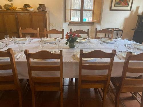 A cozy dining room with a rustic wooden table set for a meal, surrounded by chairs, evokes a warm, inviting atmosphere perfect for a family gathering or intimate dinner party.