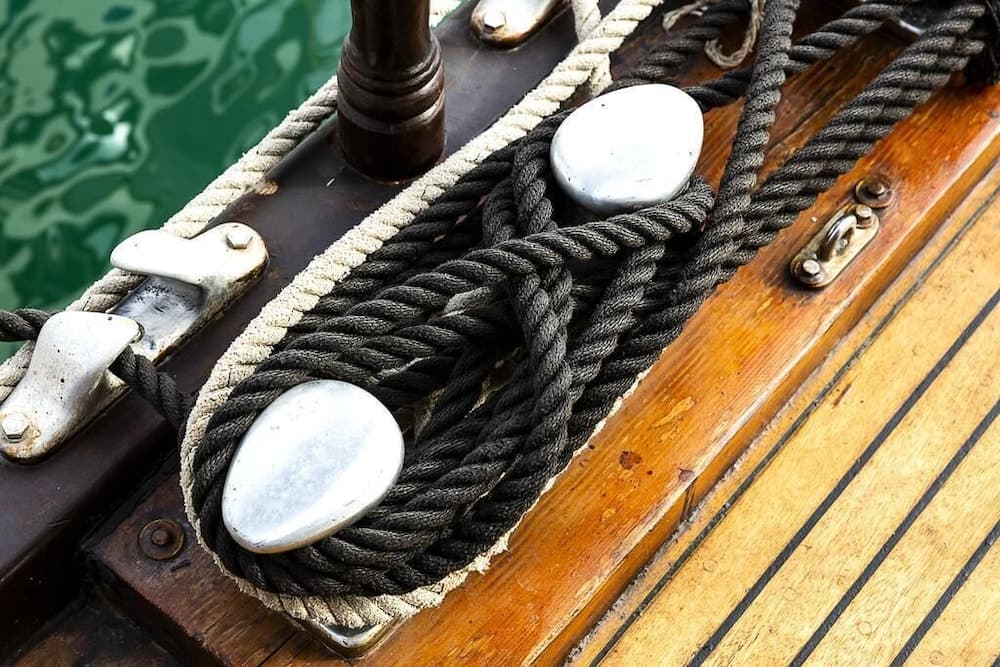 A close-up of coiled ropes on a wooden boat deck by the water, ideal for nautical enthusiasts exploring maritime settings.