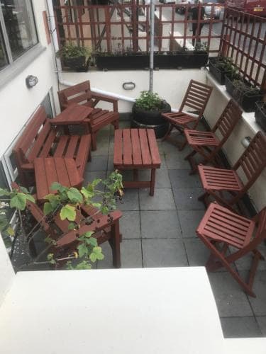 A cozy outdoor patio with wooden furniture and potted plants creates an inviting atmosphere, perfect for travelers seeking a relaxing spot to unwind in a city setting.