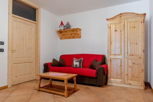 A cozy living room with wooden furnishings, a red sofa adorned with pillows, and festive gnome decorations creates a warm and inviting atmosphere ideal for a relaxing vacation rental stay.