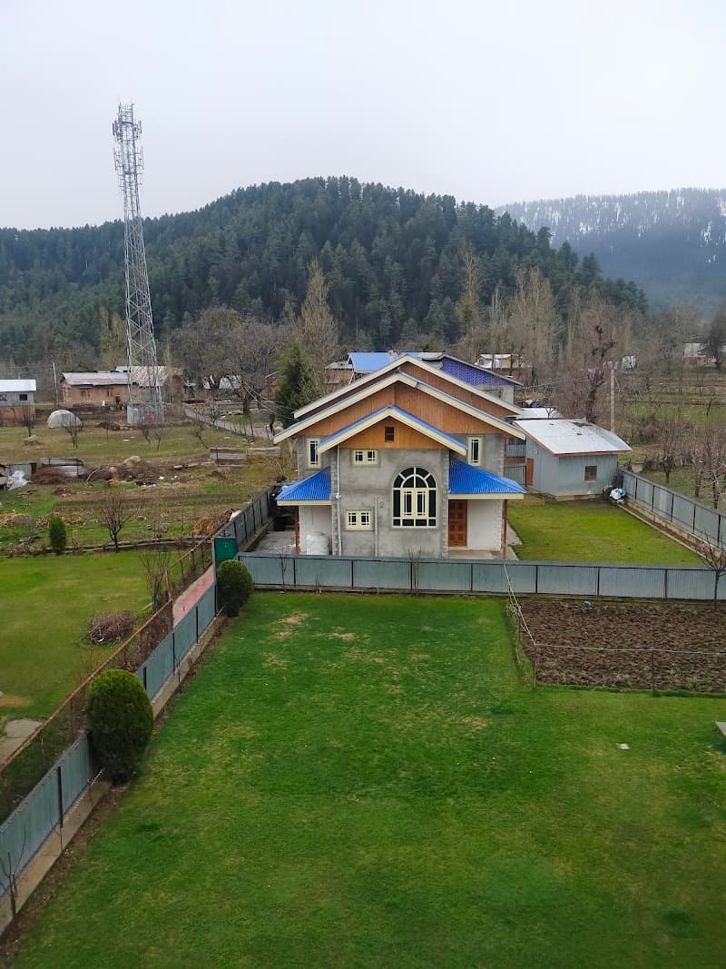 A serene countryside cottage with a lush green lawn and forested hills in the background offers a tranquil retreat for travelers seeking peace and natural beauty.