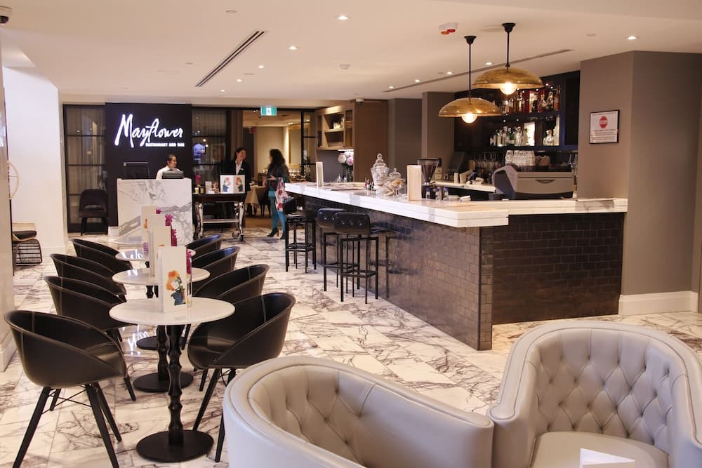 A modern, upscale restaurant and bar features sleek marble floors, plush seating, and elegant lighting, creating an inviting atmosphere ideal for business meetings or romantic dinners.