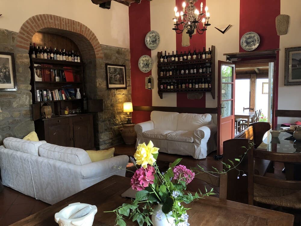 A cozy, rustic living room with stone walls, warm lighting, and wine racks exudes charm, perfect for travelers seeking a relaxing retreat in a traditional European villa.