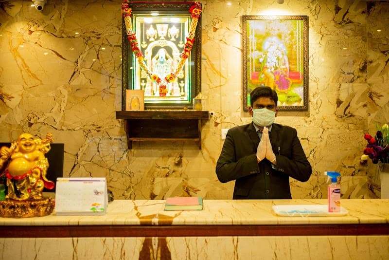 A warmly lit hotel reception in Rameshwaram, Tamil Nadu, features a marble counter adorned with religious artwork and a welcoming staff member, ideal for travelers seeking cultural immersion and hospitality.