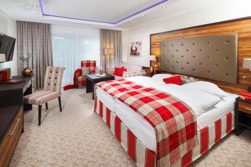 A cozy hotel room features a plush bed with red plaid bedding, modern furnishings, and soft lighting, creating a welcoming atmosphere ideal for travelers seeking comfort and relaxation.