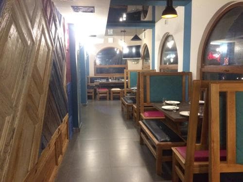 A cozy restaurant interior with wooden furniture, arched windows, and warm lighting creates an inviting atmosphere, perfect for travelers seeking a relaxing dining experience.