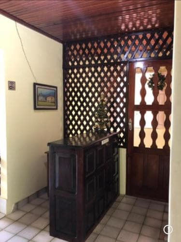 A cozy indoor reception area features a wooden lattice wall, tiled floor, and festive Christmas tree, creating a warm and inviting atmosphere ideal for travelers seeking a charming accommodation experience.