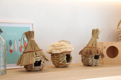 A cozy indoor shelf displays intricately woven straw birdhouses alongside a wooden box, evoking a rustic charm ideal for home decor enthusiasts exploring eco-friendly crafts.