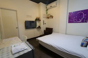 A cozy hotel room features a neatly made bed, vibrant wall art, and a small dining area, creating an inviting atmosphere ideal for solo travelers seeking comfort and simplicity.