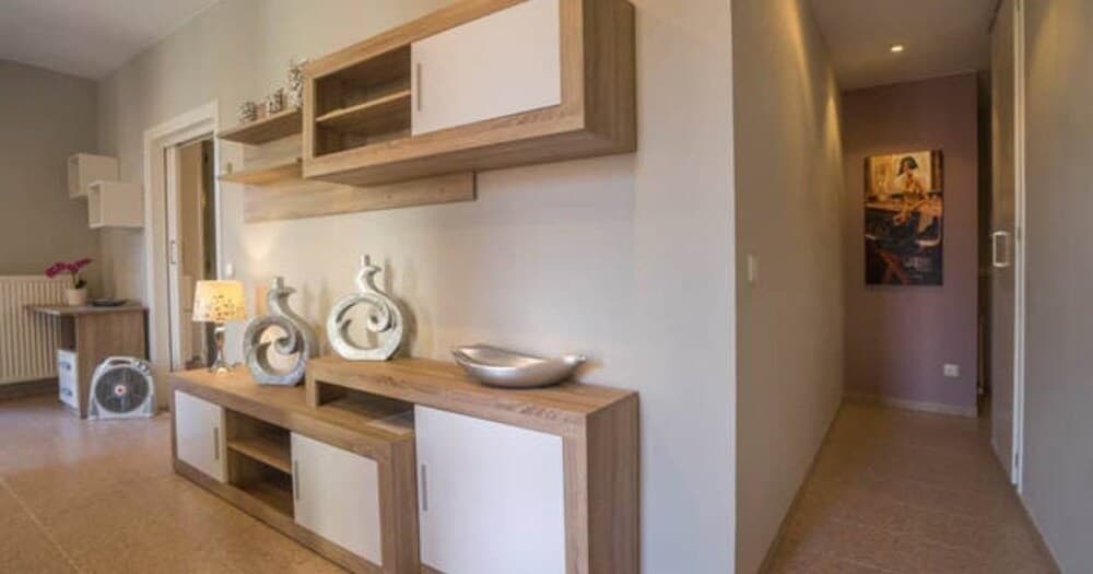 A cozy apartment hallway features modern wooden furniture adorned with decorative items, creating a welcoming atmosphere ideal for travelers seeking comfortable accommodations.
