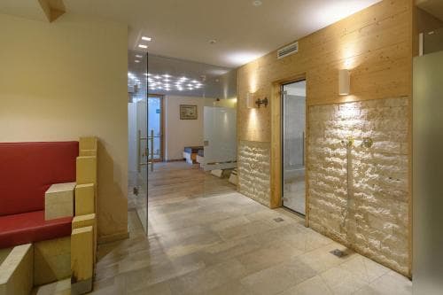 A cozy spa hallway with wooden walls, illuminated stone features, and a red lounge area creates a serene atmosphere ideal for relaxation and wellness retreats.