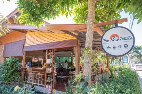 A cozy outdoor café with wooden furniture and lush greenery offers a serene retreat, perfect for travelers seeking relaxation and Wi-Fi connectivity under the shade of trees.