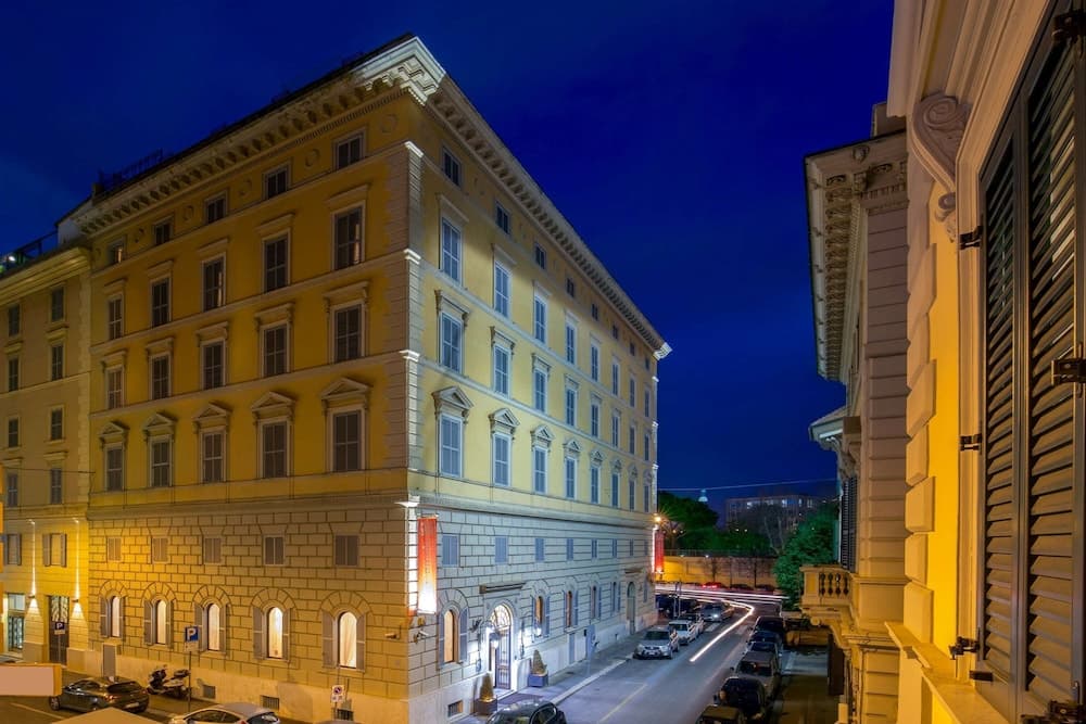 A warmly lit European city street at dusk showcases elegant architecture with arched windows and balconies, creating an inviting atmosphere ideal for urban exploration and photography.