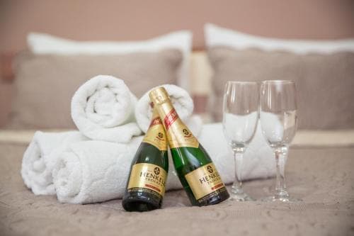 A cozy hotel room scene featuring neatly rolled white towels, two bottles of champagne, and glasses on a bed, evoking a romantic and luxurious mood ideal for honeymoon or special occasion stays.