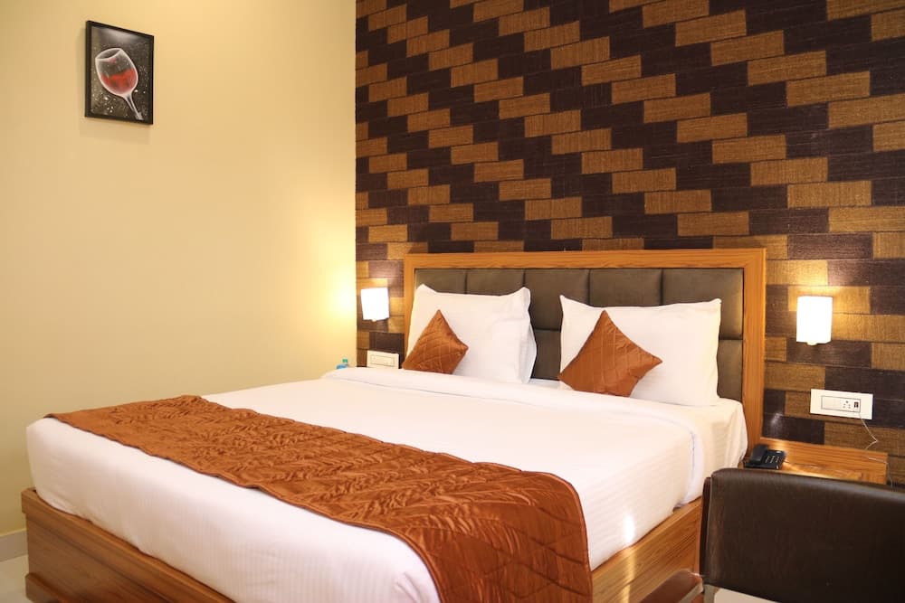 A cozy hotel room features a neatly made bed with white linens and a brown quilted runner, set against a textured brick-patterned wall, creating a warm and inviting atmosphere ideal for travelers seeking comfort and relaxation.