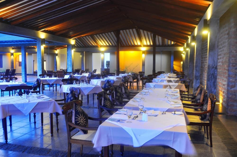An inviting outdoor dining area with wooden ceilings, brick walls, and neatly arranged tables set for an elegant meal, perfect for travelers seeking a cozy restaurant experience.