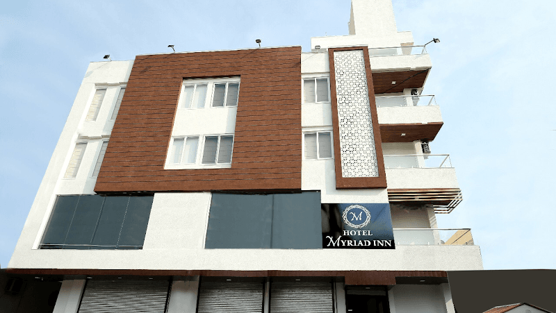 The modern facade of Hotel Myriad Inn in Jaipur, Rajasthan, features a striking blend of white and brown panels, glass balconies, and a prominent logo, creating an inviting atmosphere for travelers seeking comfort and style.
