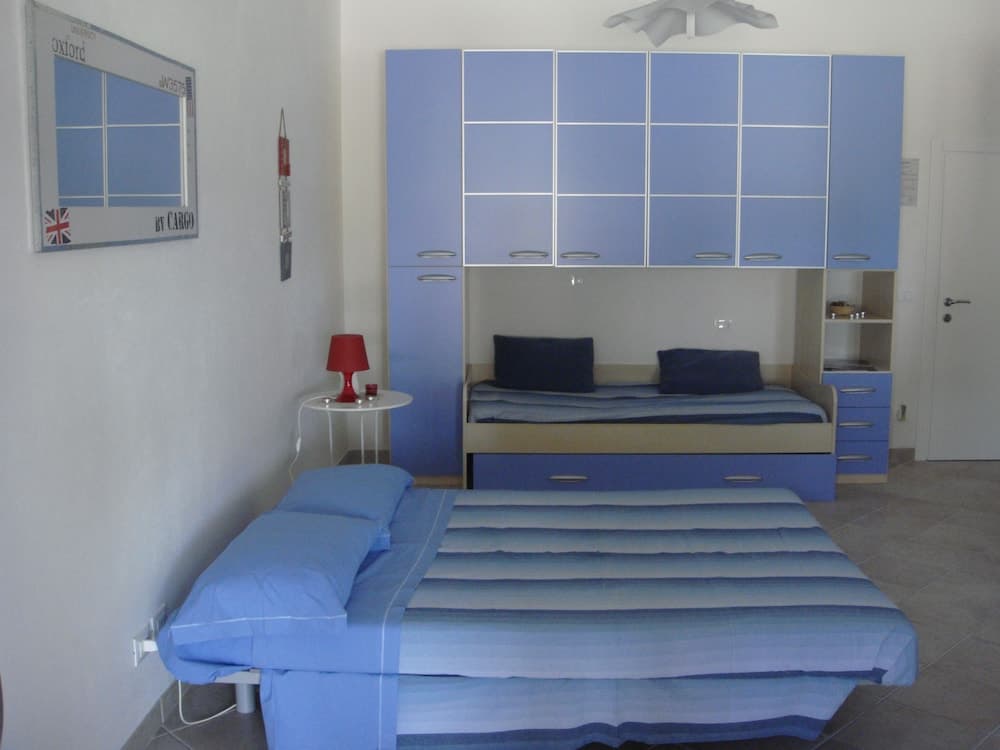 A cozy bedroom with blue-themed furnishings, including twin beds and a large storage unit, exudes a serene atmosphere ideal for travelers seeking comfort in a compact space.