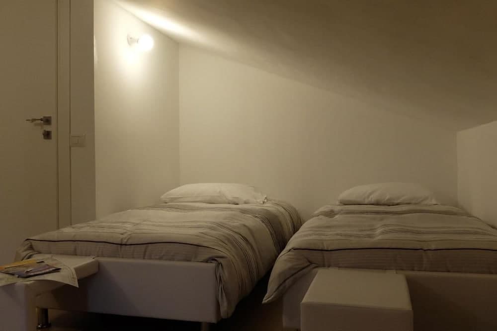 A cozy minimalist bedroom with two neatly made single beds under soft ambient lighting, ideal for travelers seeking a quiet and simple accommodation experience.