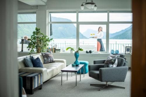 A cozy lounge area with modern furniture and large windows overlooking scenic mountains invites travelers to relax and enjoy the serene atmosphere during their stay at a luxurious retreat.