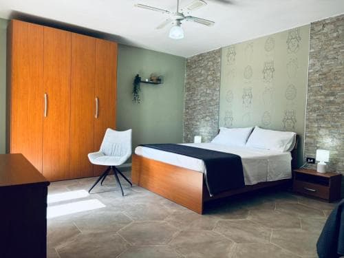 A cozy hotel room features a neatly made bed, wooden furnishings, and textured walls, creating a welcoming atmosphere ideal for travelers seeking comfort and relaxation.